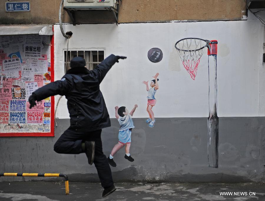 A man makes a shooting pose in front of a basketball cartoon mural in a residential community of Changsha, capital of central China's Hunan Province, Jan. 15, 2015. The exterior walls of a residential community in Changsha have been rejuvenated, after a group of young cartoonists were invited to create some 40 cartoon murals on them. The mural painters not only drew on plain walls, but also blended their work with the environment by integrating objects on the scene (newspaper boxes, electricity meter cases, air-conditioning units, etc.) into the murals. (Xinhua/Li Ga)