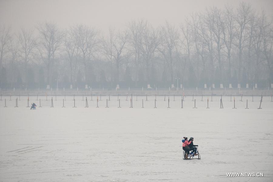 Tourists play a sledge on the frozen Kunming Lake in the Summer Palace of Beijing, capital of China, Jan. 14, 2015. Beijing on Wednesday saw a snowfall while the city was enveloped by heavy smog. The city's meteorological station recorded snowfall of less than 1 millimeter in the morning, with the snow likely to continue into the evening. (Xinhua/Li Xin)