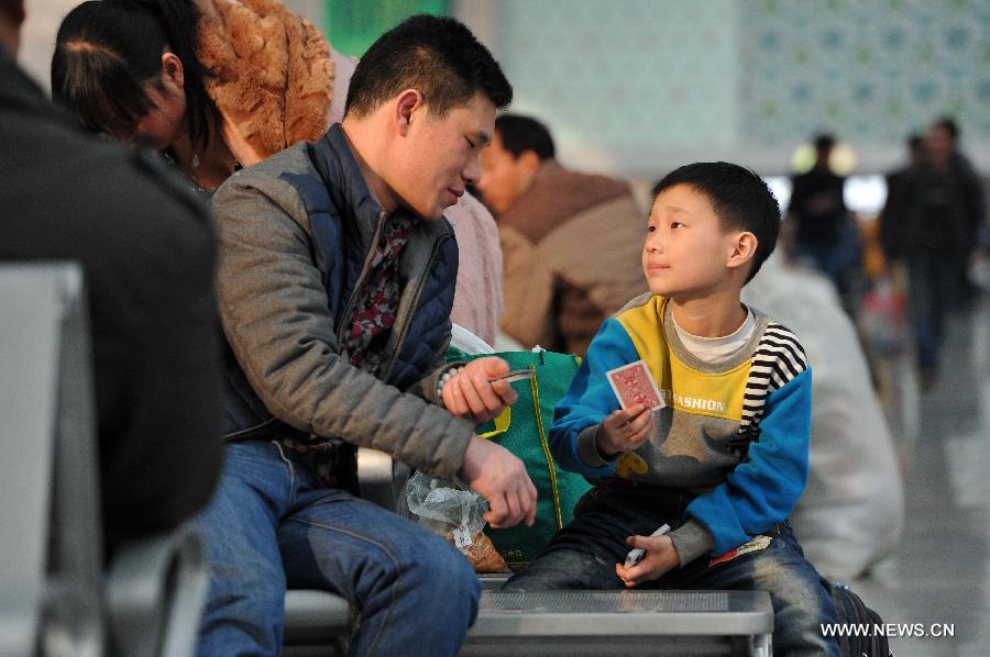 Eight-year-old Wang Chuanning plays poker with his father while waiting for their train home at the railway station of Yinchuan, capital of northwest China's Ningxia Hui Autonomous Region, Feb. 2, 2015. 