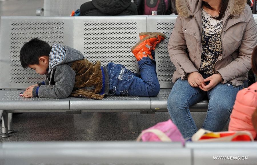 The six-year-old Liu Yuchen plays on a chair while waiting for their train home with his mother at the railway station of Yinchuan, capital of northwest China's Ningxia Hui Autonomous Region, Feb. 2, 2015. 