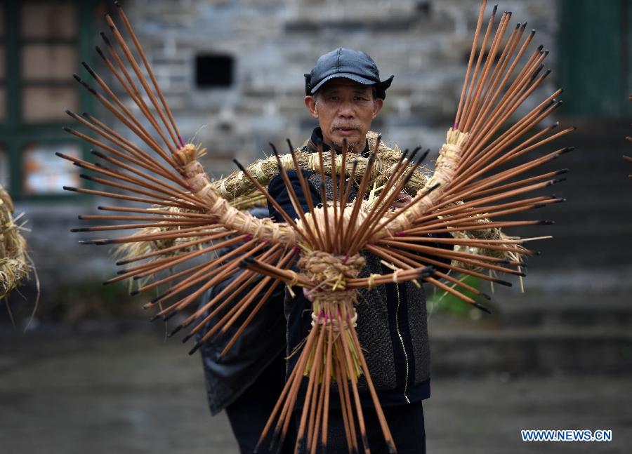 Villager Wang Xiaoqing shows incense-inserted straw bundles in Zhengyuan Village of Qidu Township in Chenzhou City, central China's Hunan Province, March 3, 2015. Local villagers, who has a tradition to worship farm cattle, followed the custom to tie red flowers on cattle and perform bullfight dance with straw bundles which are inserted with litten incenses on the 13th day of the first month of the lunar year. (Xinhua/Li Ga) 