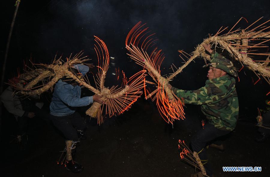 Villagers perform bullfight dance called 'Huoxianniu' (fire fairy cattle) with incense-inserted straw bundles in Zhengyuan Village of Qidu Township in Chenzhou City, central China's Hunan Province, March 3, 2015. Local villagers, who has a tradition to worship farm cattle, followed the custom to tie red flowers on cattle and perform bullfight dance with straw bundles which are inserted with litten incenses on the 13th day of the first month of the lunar year. (Xinhua/Li Ga) 