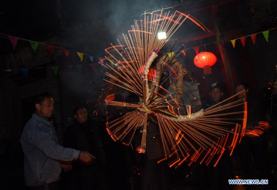 A villager performs bullfight dance called 'Huoxianniu' (fire fairy cattle) with incense-inserted straw bundles in Zhengyuan Village of Qidu Township in Chenzhou City, central China's Hunan Province, March 3, 2015. Local villagers, who has a tradition to worship farm cattle, followed the custom to tie red flowers on cattle and perform bullfight dance with straw bundles which are inserted with litten incenses on the 13th day of the first month of the lunar year. (Xinhua/Li Ga)  