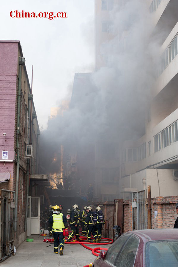 Firefighters pump water into a blazing building in a residential area in downtown Beijing on Thursday, March 5, the traditional Chinese Lantern Festival. The building located between Linglong Rd. and Qixiancun Rd. in Haidian District, is used as a warehouse of Gehua, Beijing's local cable TV service provider. The burning rubber from the cable wire gives out a strong black smoke. [Photo by Chen Boyuan / China.org.cn]