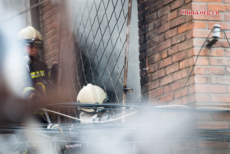 Firefighters try to break into a blazing building in a residential area in downtown Beijing on Thursday, March 5, the traditional Chinese Lantern Festival. The building is located between Linglong Rd. and Qixiancun Rd. in Haidian District, is used as a warehouse of Gehua, Beijing's local cable TV service provider. The burning rubber from the cable wire gives out a strong black smoke. [Photo by Chen Boyuan / China.org.cn]