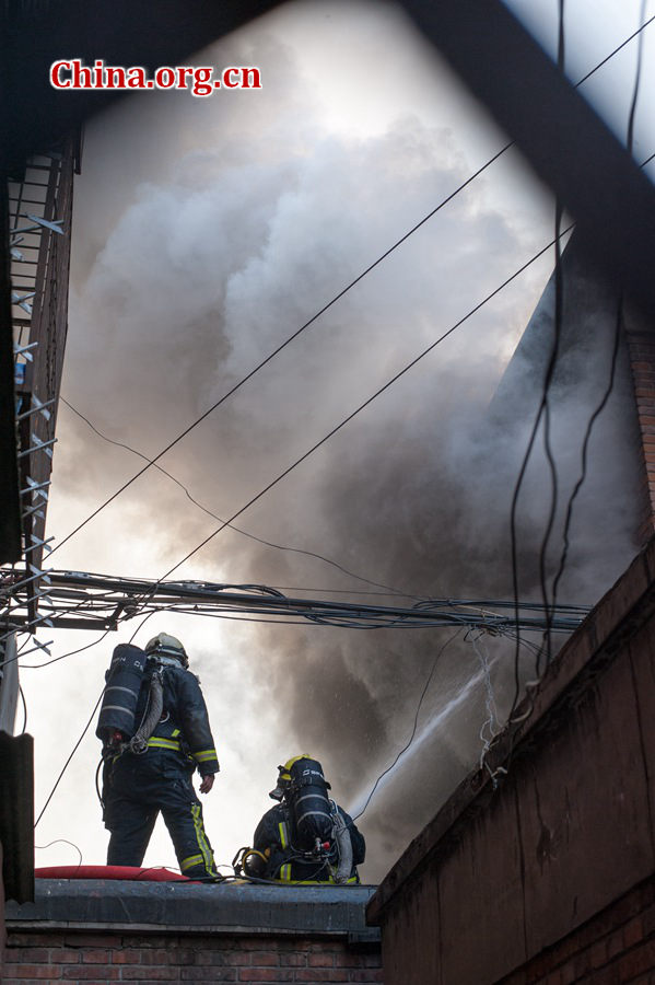 Firefighters pump water into a blazing building in a residential area in downtown Beijing on Thursday, March 5, the traditional Chinese Lantern Festival. The building located between Linglong Rd. and Qixiancun Rd. in Haidian District, is used as a warehouse of Gehua, Beijing's local cable TV service provider. The burning rubber from the cable wire gives out a strong black smoke. [Photo by Chen Boyuan / China.org.cn]