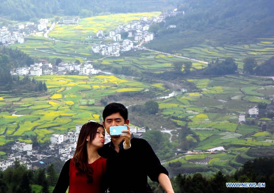 A couple take selfie in front of cole flower fields in Wuyuan County, east China's Jiangxi Province, March 31, 2015. The cole flower fields make Wuyuan the reputation of the most beautiful village in spring. (Xinhua/Wang Song)