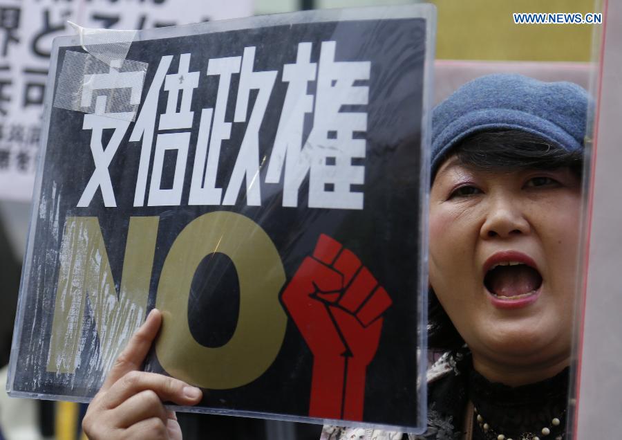 A woman holds a placard during a demonstration to protest against the revision of the pacifist Article 9 of the Japanese Constitution in Tokyo, Japan, April 11, 2015.