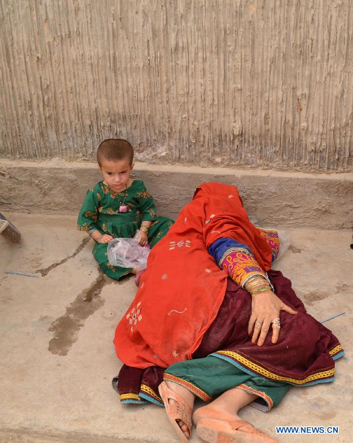 A mother takes a nap as her daughter sits beside her on a road in southwest Pakistan's Quetta on May 10, 2015, the Mother's Day