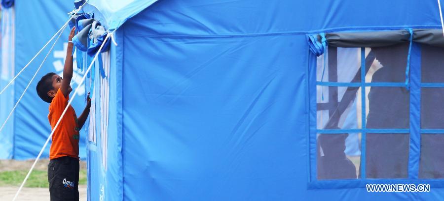 A boy arranges his tent at a temporary settlement at Tundikhel in Kathmandu, Nepal, May 16, 2015.