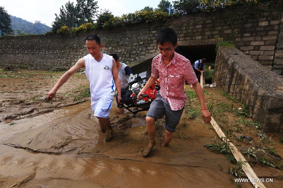 Villagers carry a pump to drain water after rainstorms in Leishan County, southwest China's Guizhou Province, May 28, 2015. Leishan County lost access to power and water supplies after torrential rain battered the area from Tuesday night to Wednesday. The rescue work is underway. 