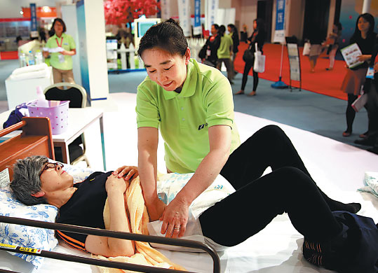 A nursing worker attending the fourth China International Senior Services Expo in Beijing on May 6 shows how she cares for the elderly. （Photo： Pan Xu/Xinhua）