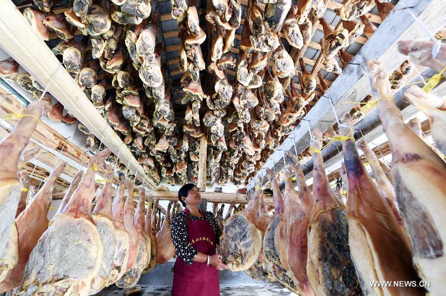 Farmer Shi Wanglian cuts homemade cured hams at Anzhao Village of Jingdong County, southwest China's Yunnan Province, June 2, 2015.