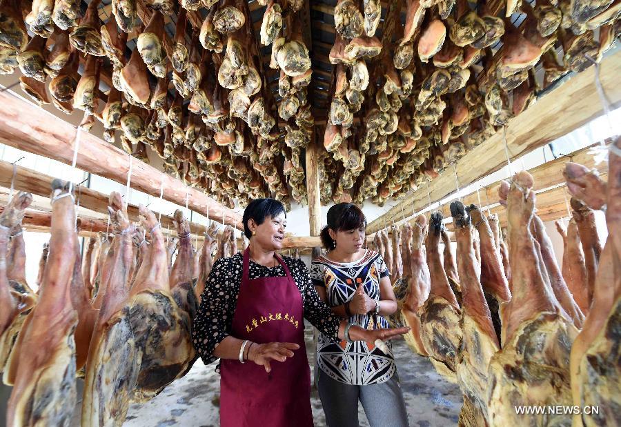 Farmer Shi Wanglian cuts homemade cured hams at Anzhao Village of Jingdong County, southwest China's Yunnan Province, June 2, 2015.