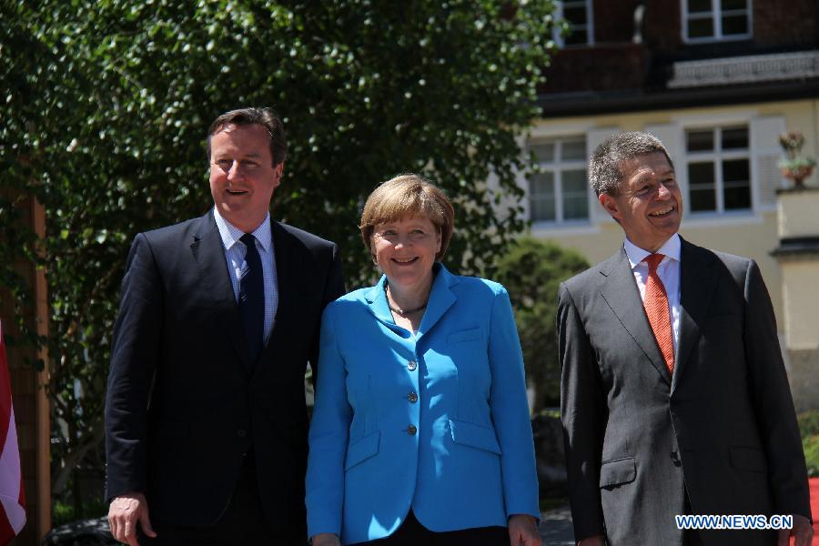 German Chancellor Angela Merkel (C) welcomes British Prime Minister David Cameron (L) at the Elmau Castle near Garmisch-Partenkirchen, southern Germany, on June 7, 2015. 