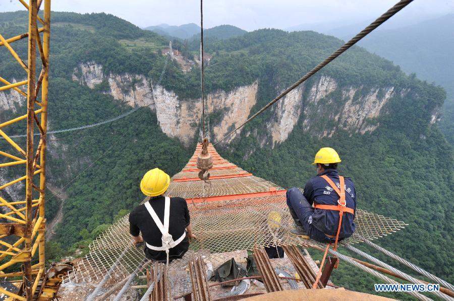 Workers build the vitreous bridge above the grand canyon in Zhangjiajie, central China's Hunan Province, June 15, 2015.