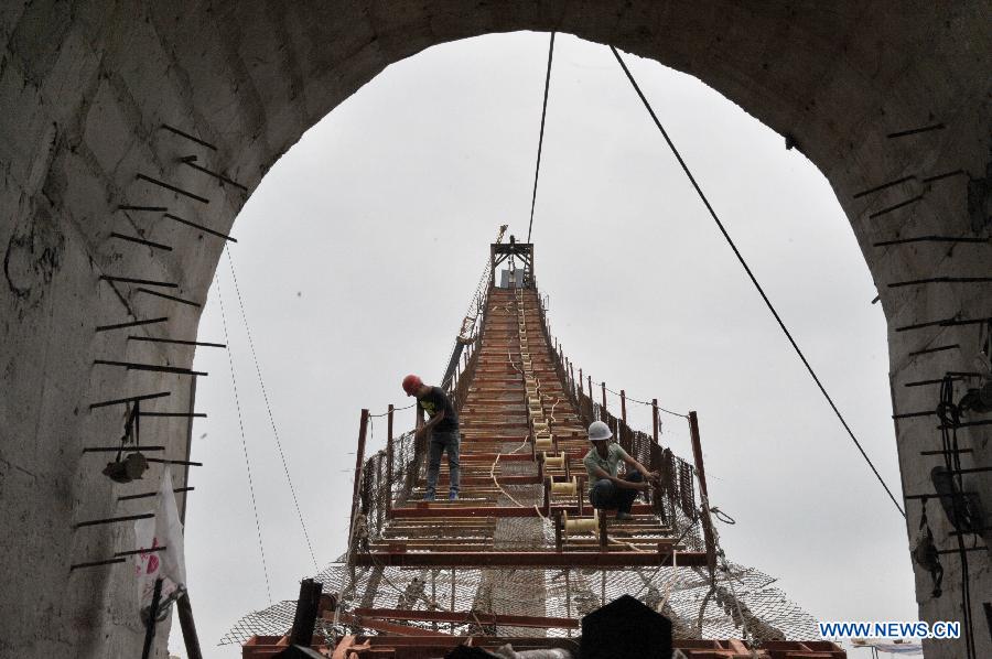 Workers check the guardrail at the construction site of a vitreous bridge above the grand canyon in Zhangjiajie, central China's Hunan Province, June 15, 2015. 