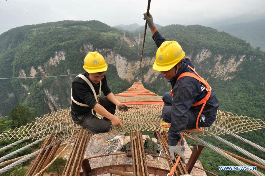 Workers build the vitreous bridge above the grand canyon in Zhangjiajie, central China's Hunan Province, June 15, 2015. 