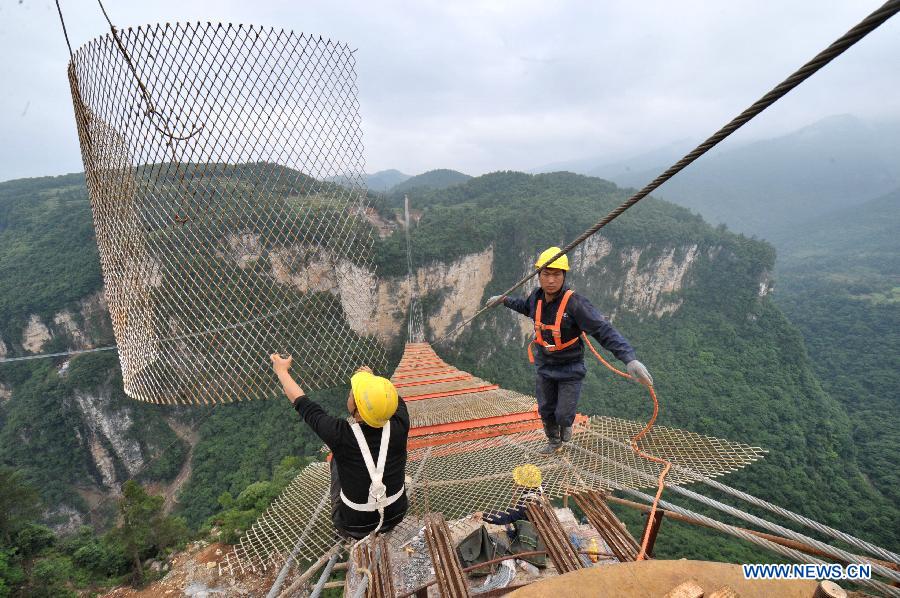 Workers build the vitreous bridge above the grand canyon in Zhangjiajie, central China's Hunan Province, June 15, 2015.