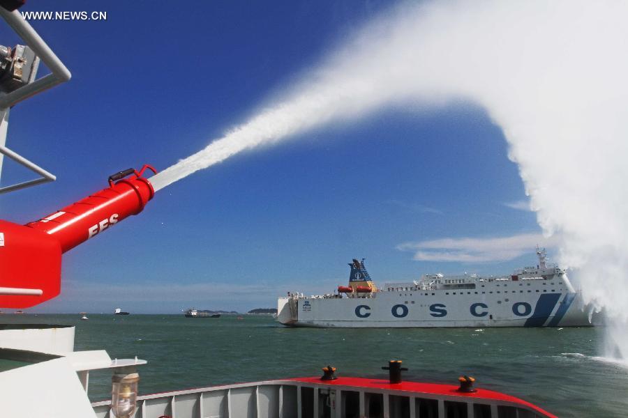 A fireboat sprays water to a passenger vessel during a rescue drill in Xiamen, southeast China's Fujian Province, June 15, 2015.