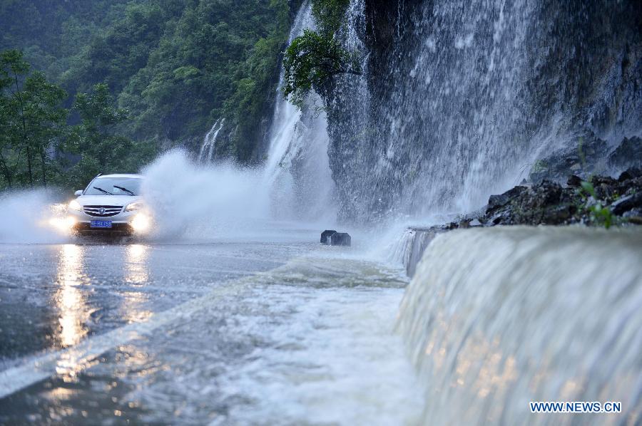 A car runs on a flooded road in Gaoluo Town of Xuan'en County, central China's Hubei Province, June 17, 2015.
