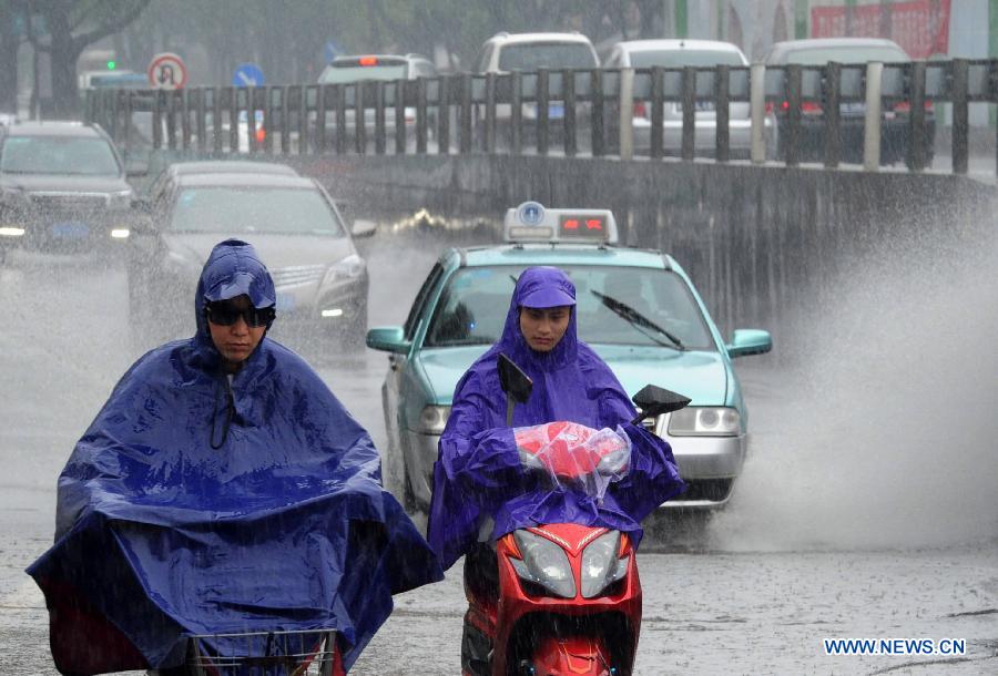 Residents brave heavy rain as they travel on a street in Suzhou, east China's Jiangsu Province, June 16, 2015. 