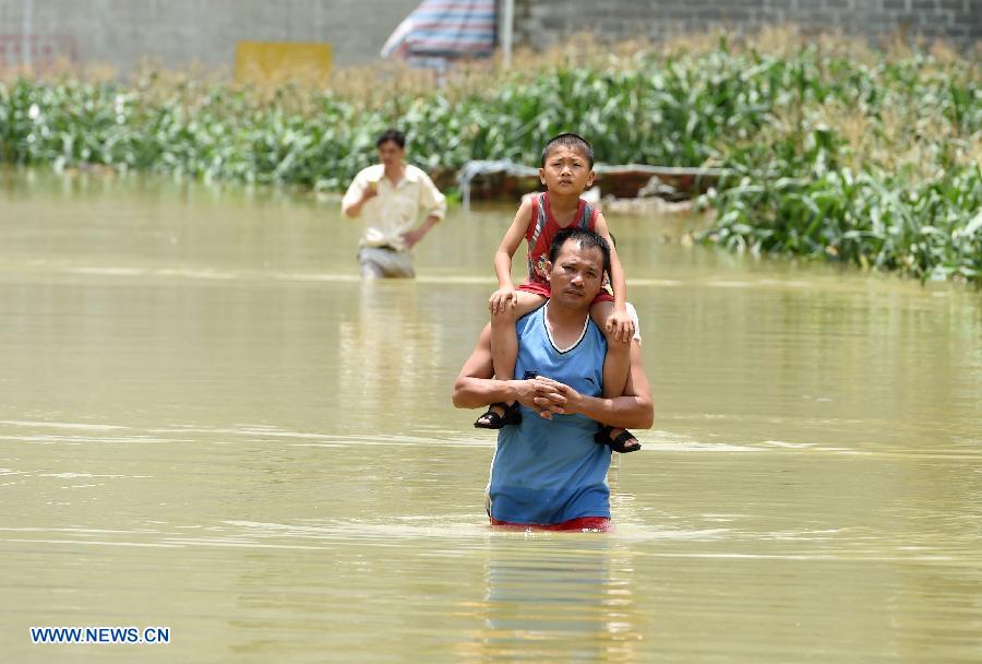 Residents wade through floodwater at Douye Village in Liuye Township of Dahua Yao Autonomous County, southwest China's Guangxi Zhuang Autonomous Region, June 16, 2015.