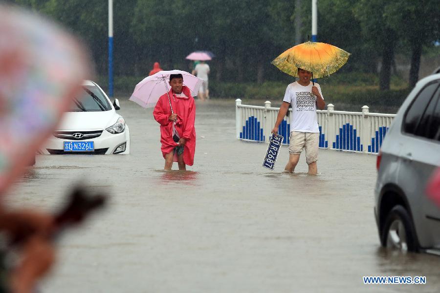 A resident picks up a car plate carried away by torrential rain on a flooded road in Changzhou, east China's Jiangsu Province, June 17, 2015.