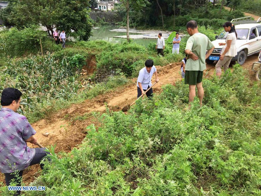 Residents repair a flood-damaged road at Huashan Village in Liuye Township of Dahua Yao Autonomous County, southwest China's Guangxi Zhuang Autonomous Region, June 16, 2015.