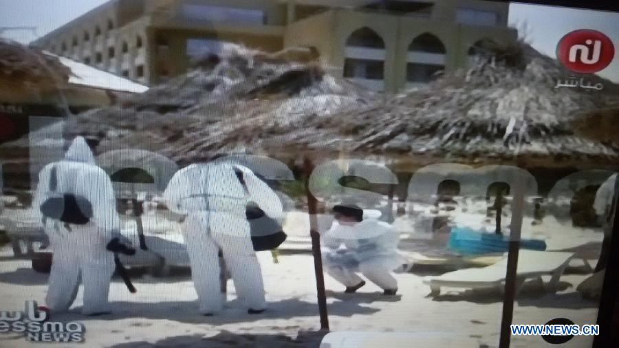 In this screenshot taken from video of NESSMA TV, Tunisian policemen collect evidence at the criminal scene of the terror attack in the coastal city of Sousse, Tunisia, June 26, 2015. 