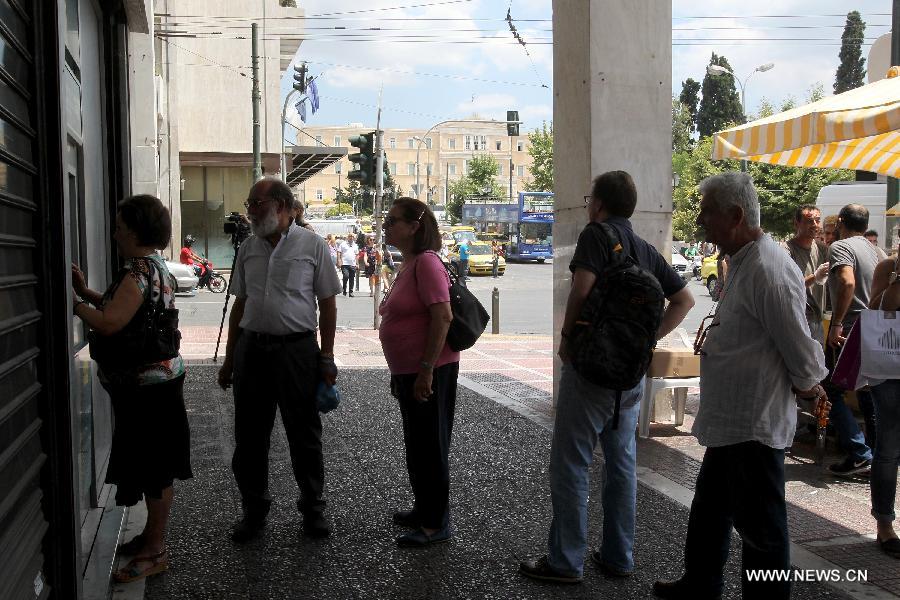 People line up at an ATM outside a National Bank branch in Athens, capital of Greece, on June 29, 2015. 