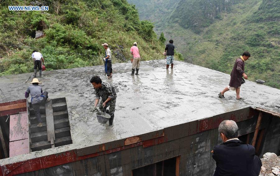 Villagers of Nongyong Village build a house along a road in Dahua Yao Autonomous County, south China's Guangxi Zhuang Autonomous Region, May 4, 2015.