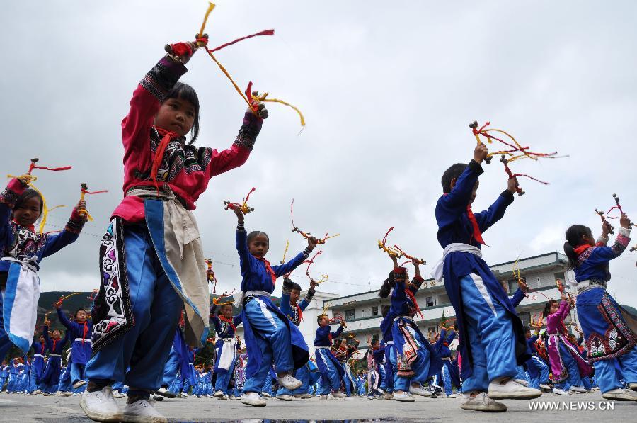 Puipls perform the traditional Yi bell dance at Bandi Elementary School in Bandi Township of Weining County, southwest China's Guizhou Province, July 1, 2015. 