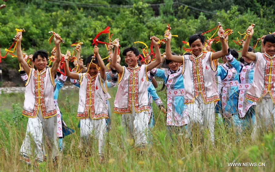 Puipls perform the traditional Yi bell dance at Bandi Elementary School in Bandi Township of Weining County, southwest China's Guizhou Province, July 1, 2015. 