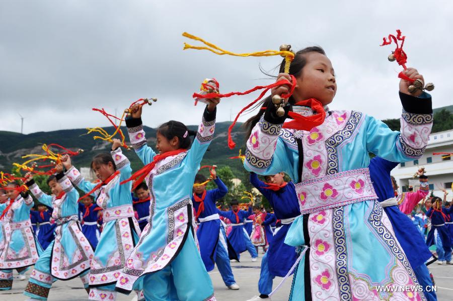 Puipls perform the traditional Yi bell dance at Bandi Elementary School in Bandi Township of Weining County, southwest China's Guizhou Province, July 1, 2015. 