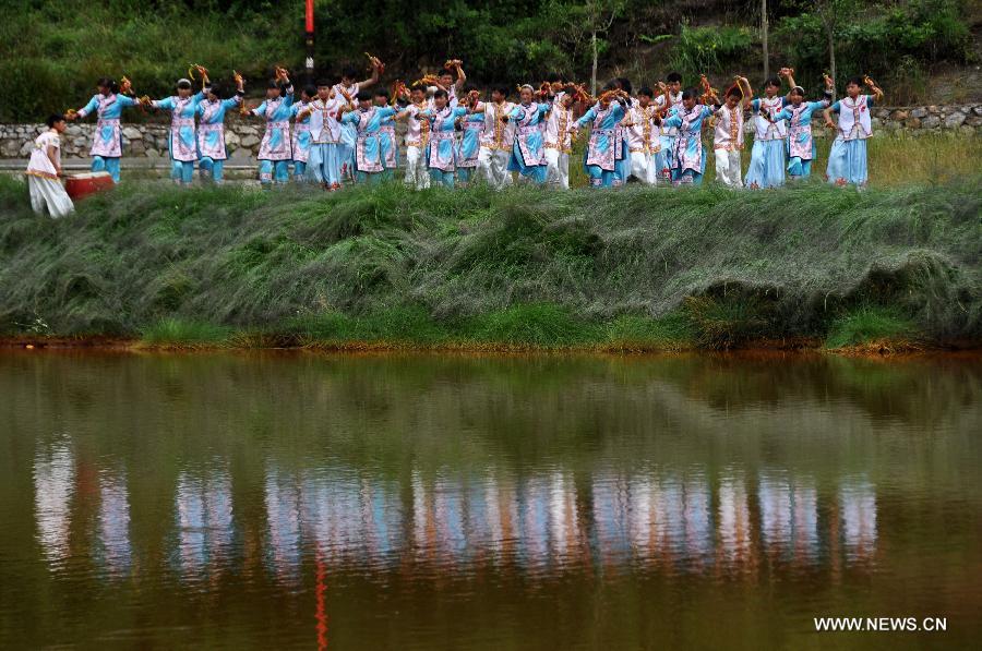 Puipls perform the traditional Yi bell dance at Bandi Elementary School in Bandi Township of Weining County, southwest China's Guizhou Province, July 1, 2015. 