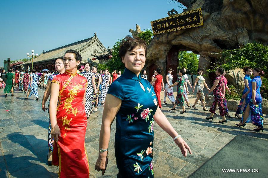 Models present cheong-sam creations during a commonweal activity at the Dahuaishu scenic zone in Hongtong County, north China's Shanxi Province, July 4, 2015. 