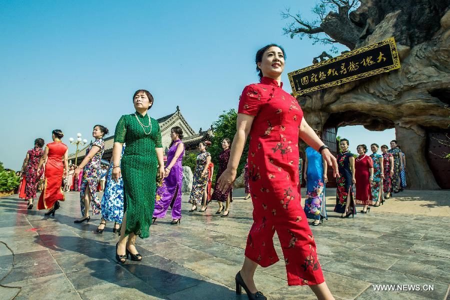 Models present cheong-sam creations during a commonweal activity at the Dahuaishu scenic zone in Hongtong County, north China's Shanxi Province, July 4, 2015. 