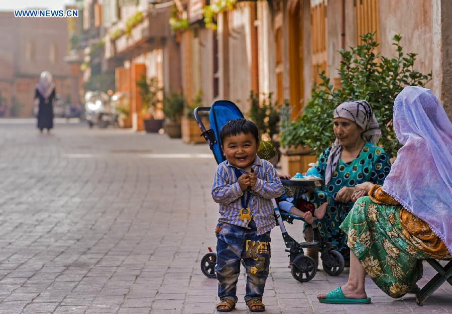 Photo taken on June 7, 2015 shows residents on a street in the old town of the old town of Kax, northwest China's Xinjiang Uygur Autonomous Region. 