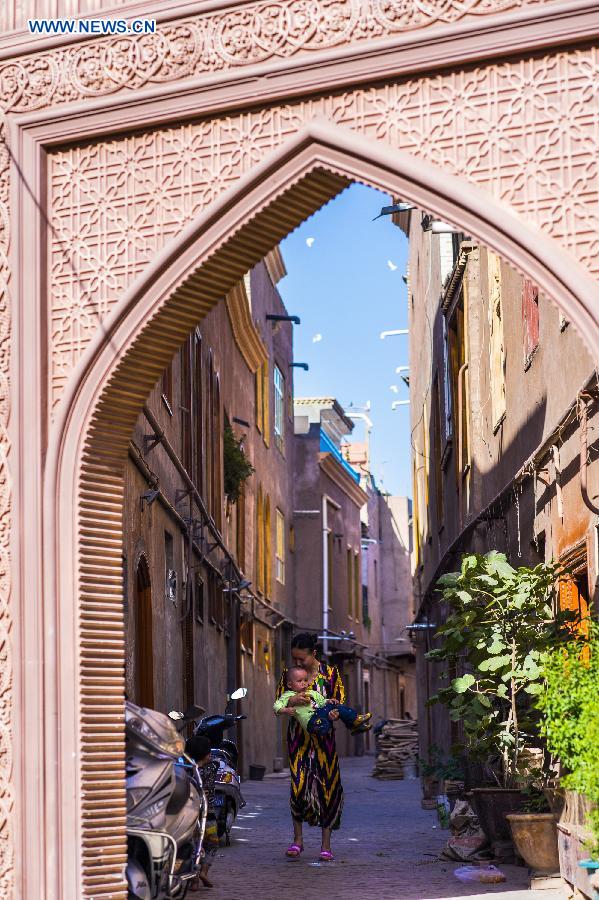 Photo taken on June 7, 2015 shows residents walking on a street in the old town of the old town of Kax, northwest China's Xinjiang Uygur Autonomous Region. 