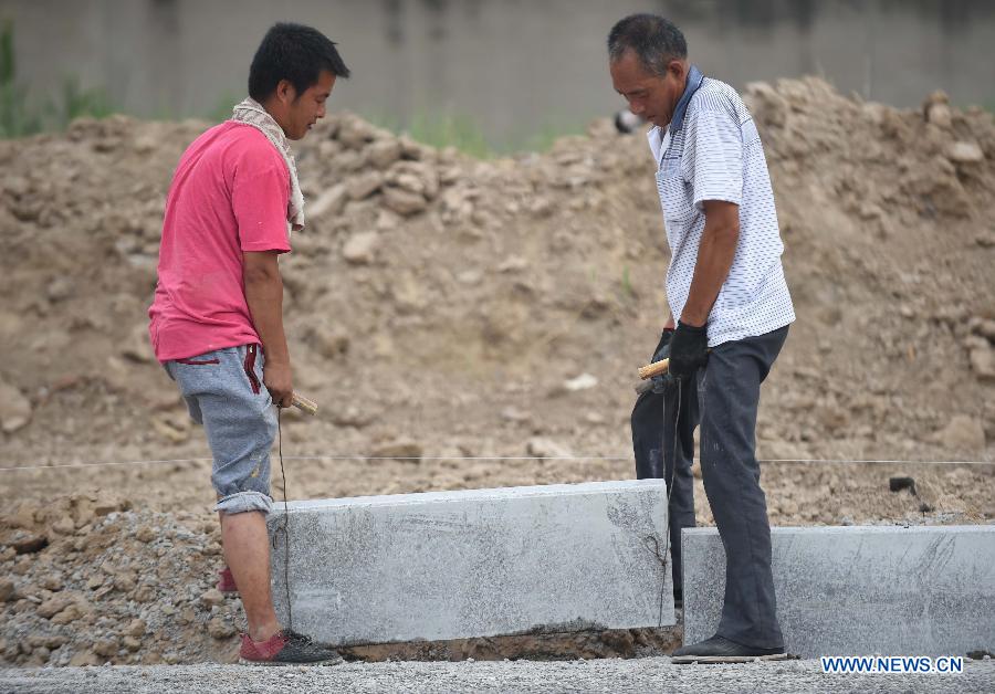 Laborers work under hot weather in Dacheng County of Langfang city, north China's Hebei Province, July 13, 2015. 