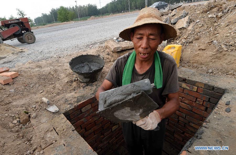 A laborer works under hot weather in Dacheng County of Langfang city, north China's Hebei Province, July 13, 2015. 