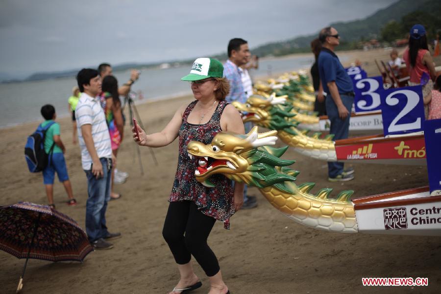 A woman takes a picture with a boat during the first festal event of Chinese dragon boat racing in Panama City, Panama, on July 12, 2015. The event attracted hundreds of people to join in.