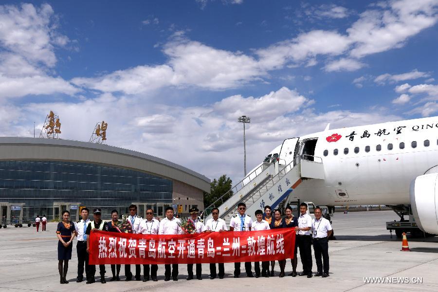 Flight and ground crew members pose for photo after the first flight from Qingdao to Dunhuang arrived at Dunhuang Airport in Dunhuang, northwest China's Gansu Province, July 16, 2015. 