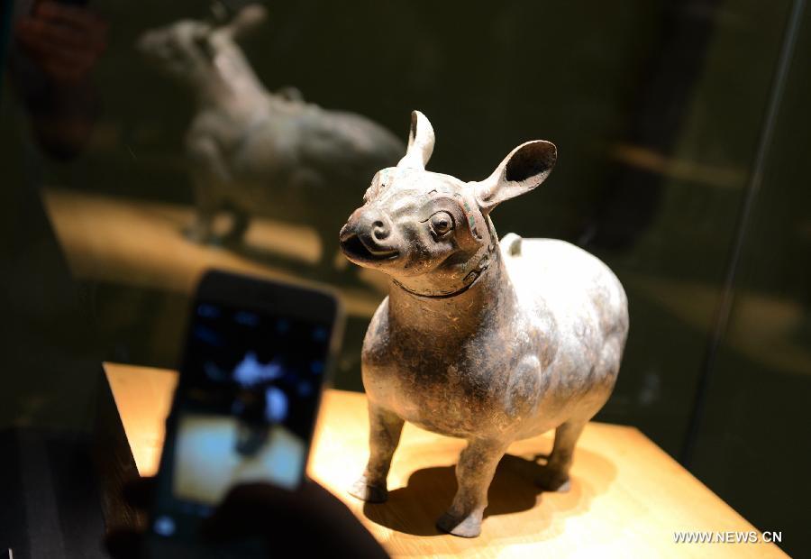 A spectator takes photos of a cultural relic during a historic and cultural exhibiton of Qi(1046BC-221BC), an ancient Chinese state during the Zhou Dynasty of ancient China, in Xi'an, capital of northwest China's Shaanxi Province, July 16, 2015. 