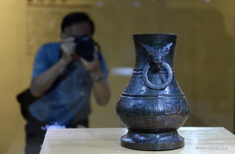 A man takes photos of a cultural relic during a historic and cultural exhibiton of Qi(1046BC-221BC), an ancient Chinese state during the Zhou Dynasty of ancient China, in Xi'an, capital of northwest China's Shaanxi Province, July 16, 2015. 