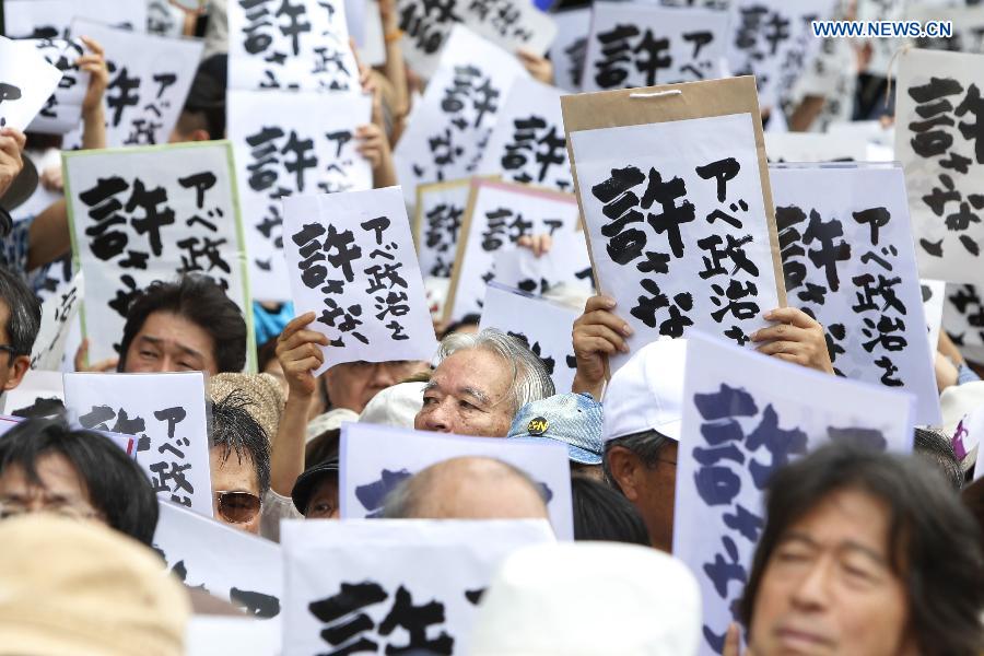 People hold placards reading 'Abe politics is unforgivable' during a rally in front of the parliament building in Tokyo, Japan, July 18, 2015. About five thousand people took part in the demonstration.