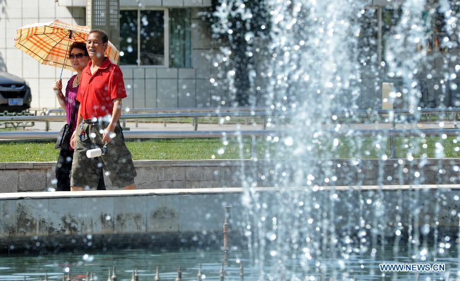 People walk past a fountain in Yinchuan, capital of northwest China's Ningxia Hui Autonomous Region, July 24, 2015. 