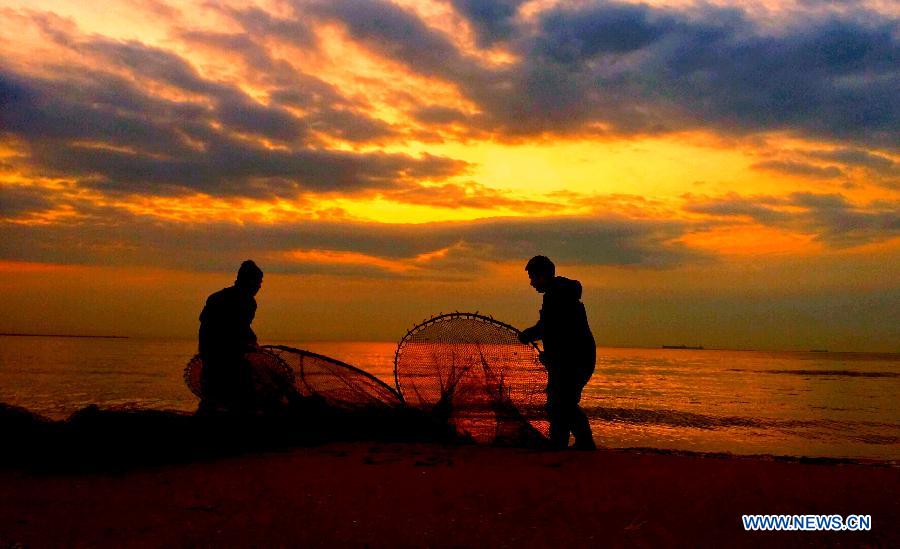 Two fishermen work on the beach in Qinhuangdao City, north China's Hebei Province, March 3, 2015.