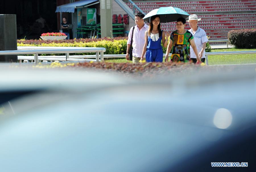 A woman holds an umbrella to shield from the scorching sun in Yinchuan, capital of northwest China's Ningxia Hui Autonomous Region, July 24, 2015. 